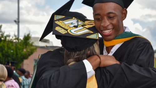 Graduates share an embrace after the ceremony